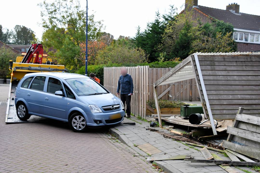 Oudere bestuurder rijdt door schutting en carport